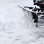 Commercial snowplow clearing heavy snow from an Ontario property