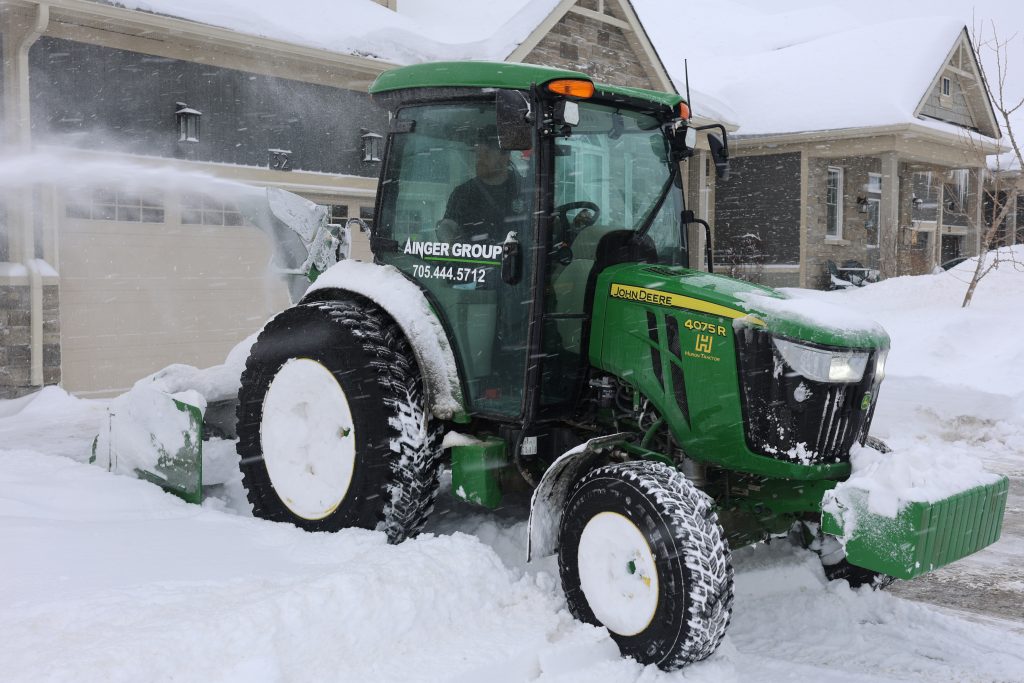 Powered snow blower equipment clearing snow at a residential property in Collingwood Ontario robot